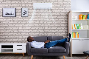 Man Using Laptop Enjoying Cooling Under Air Conditioner